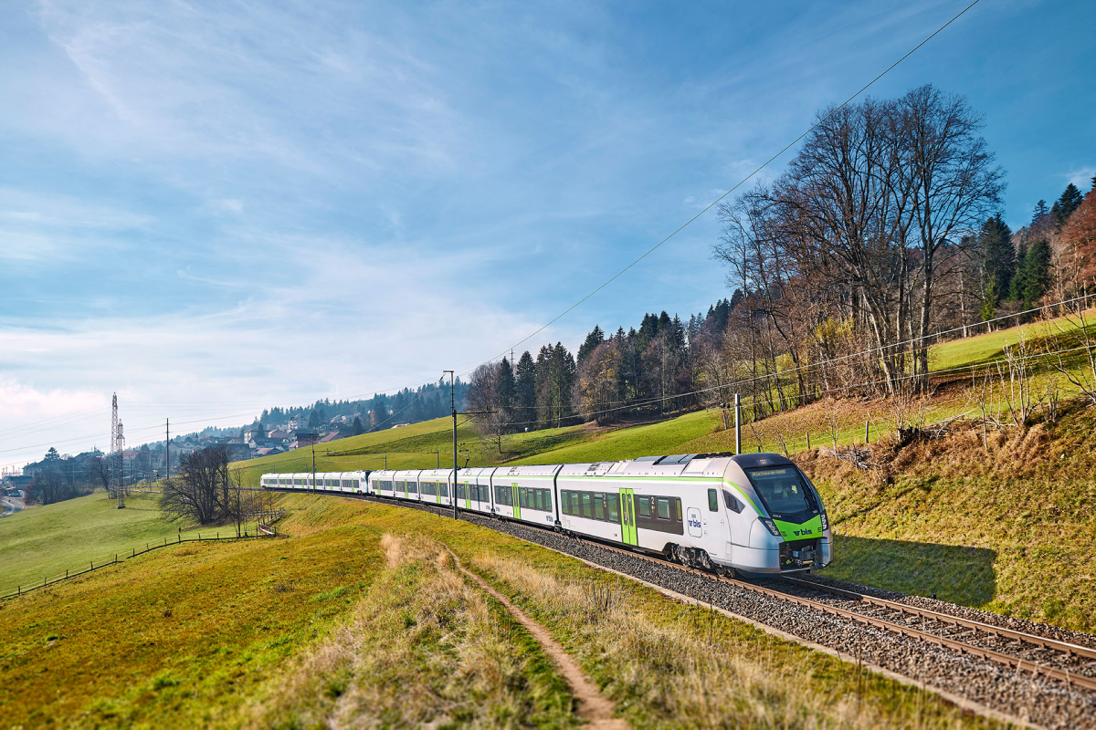 Train moving through countryside with blue sky in the background